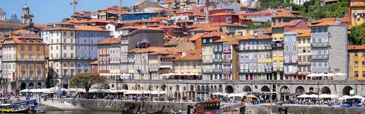 Colorful waterfront view of Ribeira District, Porto's historic charm under a bright sky.