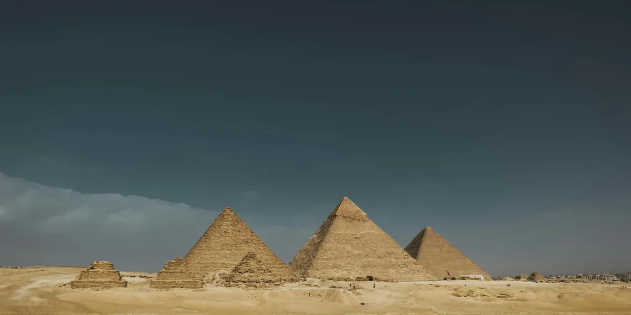 Explore the iconic Pyramids of Giza in Egypt, captured under a wide desert sky.