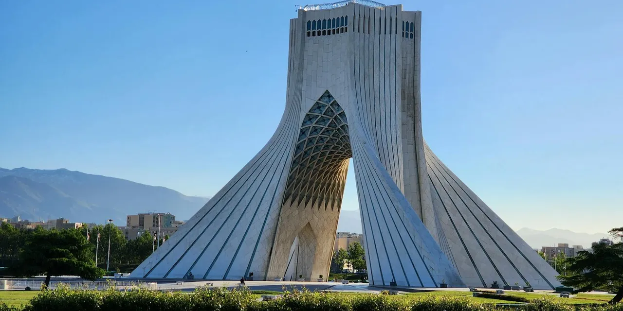 A stunning view of the Azadi Tower in Tehran, Iran, showcasing its unique architecture against a clear blue sky.
