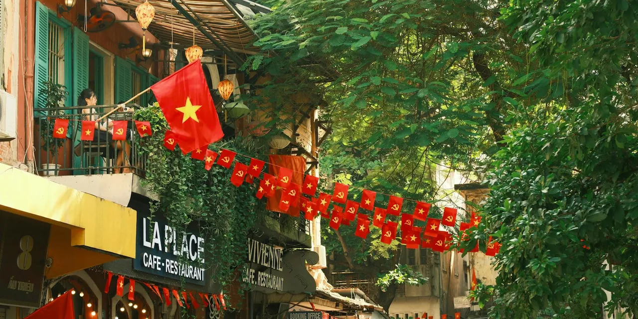 Colorful street in Vietnam adorned with vibrant flags and lush greenery.