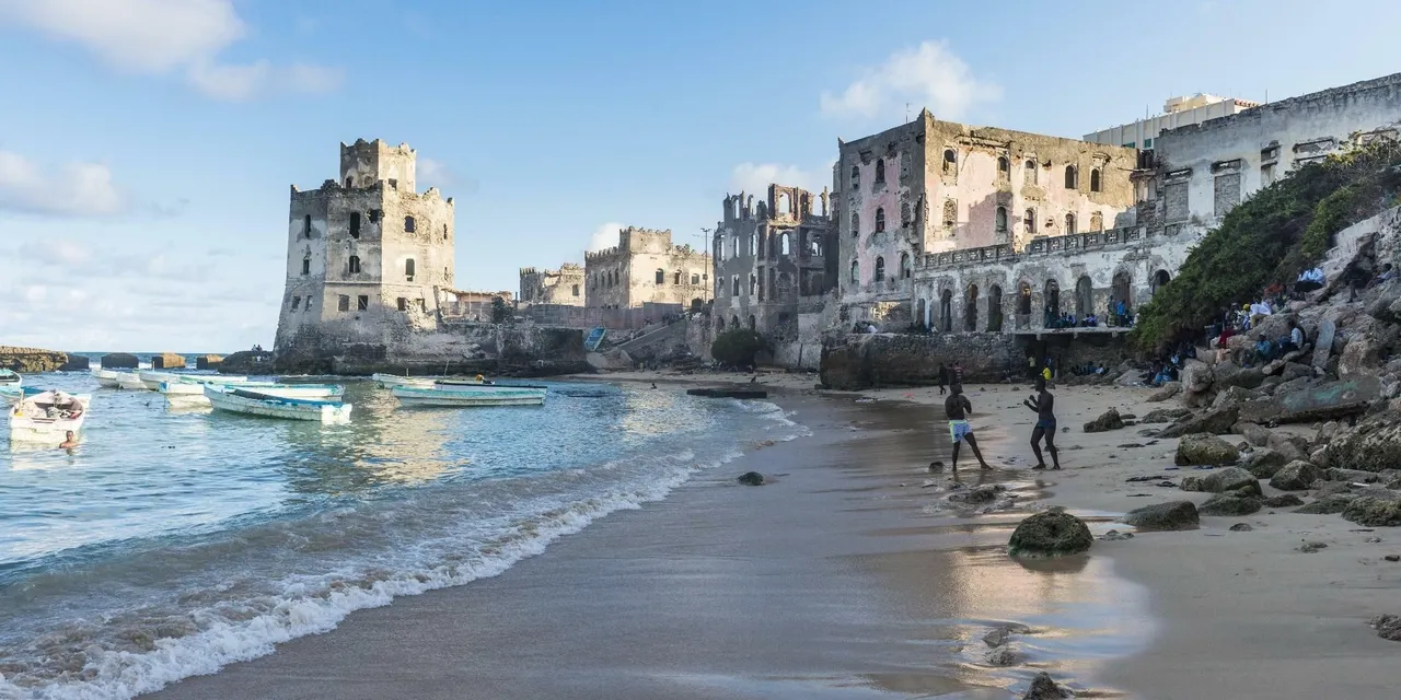 Fishing boats and children on the beach below the historic ruins of Mogadishu old town, Somalia