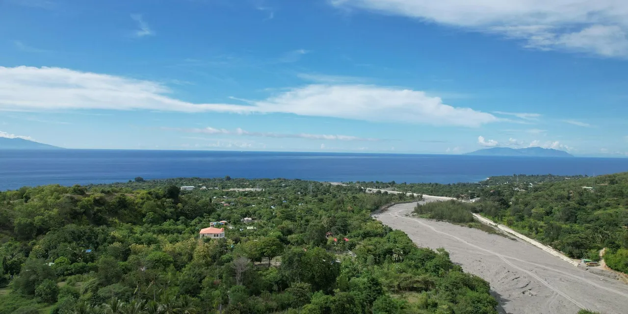 A scenic aerial view capturing the lush countryside and serene ocean of Liquica, Timor-Leste.