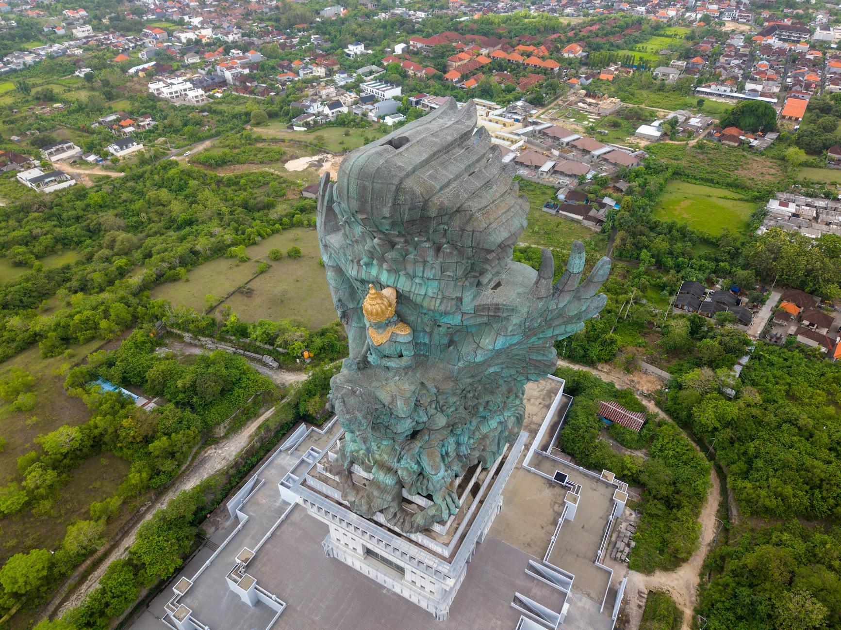 A breathtaking aerial shot of the Garuda Wisnu Kencana statue surrounded by lush greenery in Bali, Indonesia.