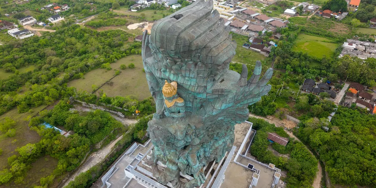 A breathtaking aerial shot of the Garuda Wisnu Kencana statue surrounded by lush greenery in Bali, Indonesia.