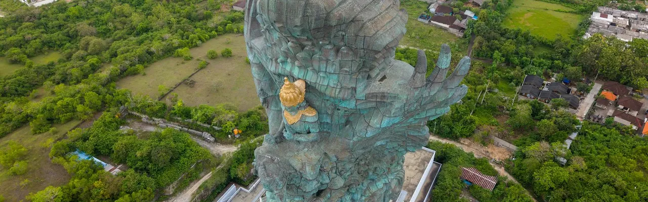 A breathtaking aerial shot of the Garuda Wisnu Kencana statue surrounded by lush greenery in Bali, Indonesia.