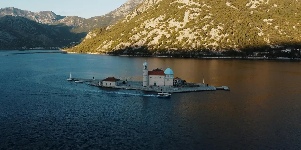 Scenic aerial view of Our Lady of the Rocks island in Perast, Montenegro, surrounded by the stunning bay.