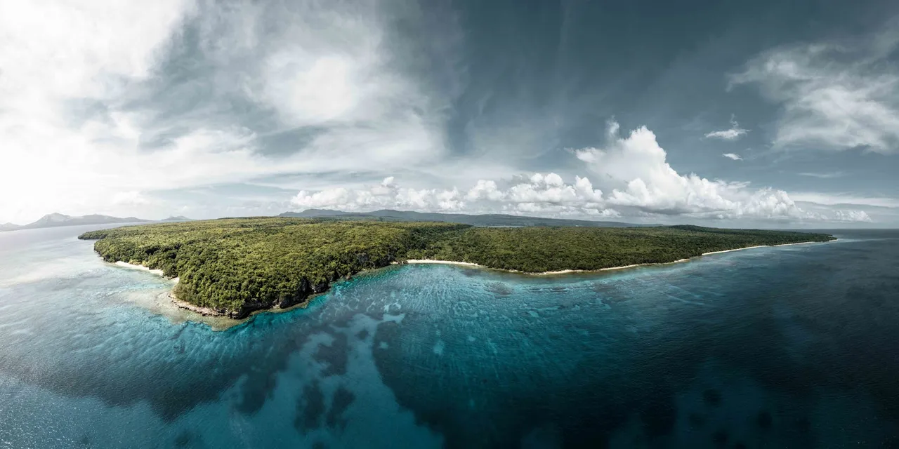 A breathtaking aerial view of the lush green coastline of Vanuatu, surrounded by crystal clear waters.