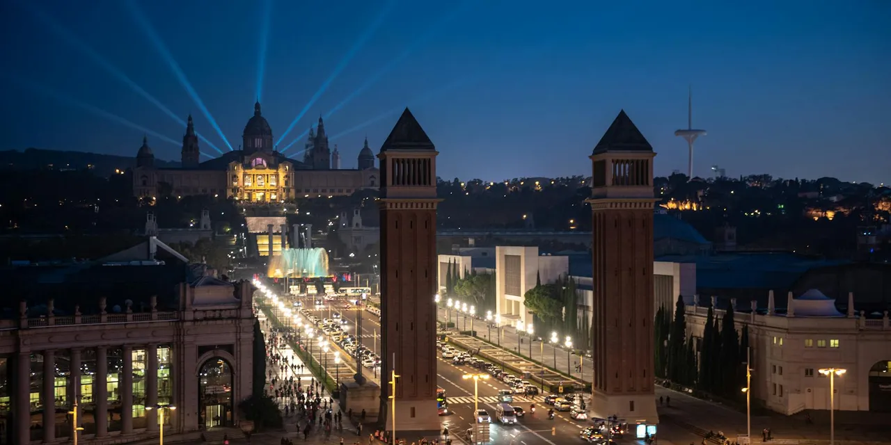 Night view of Barcelona's historic landmarks with vibrant lights and bustling streets.