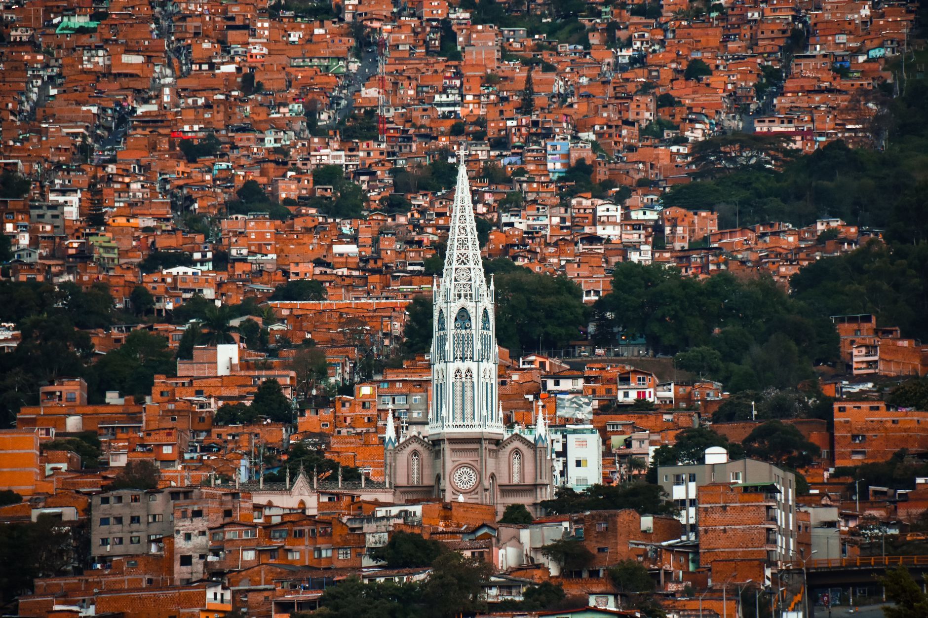 A breathtaking aerial view of Medellín, Colombia, showcasing a prominent Gothic church amidst vibrant urban sprawl.