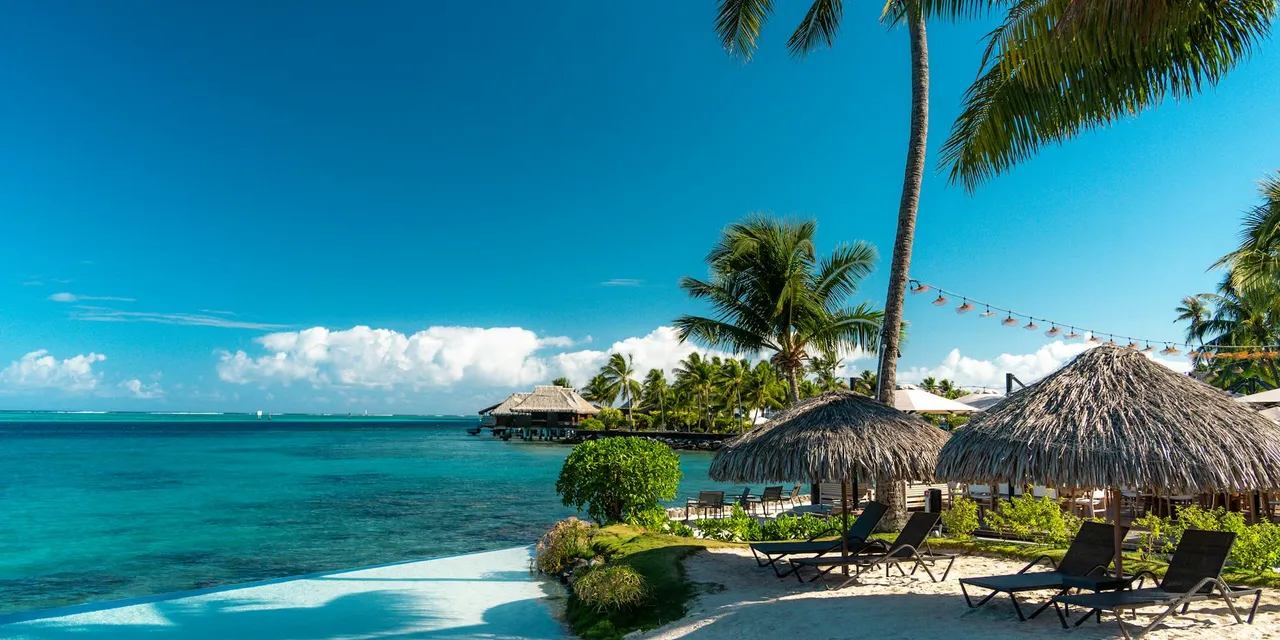 Relaxing beach scene with palm trees and huts in French Polynesia.