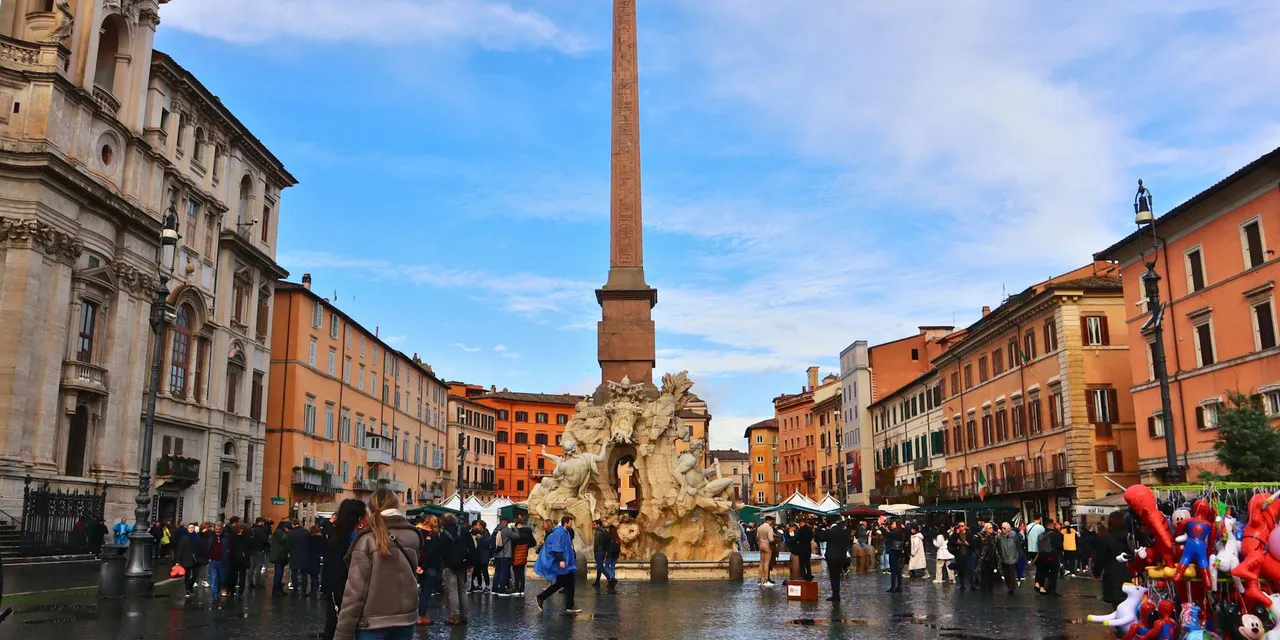A bustling scene of Piazza Navona with the iconic Fountain of the Four Rivers in Rome, Italy.