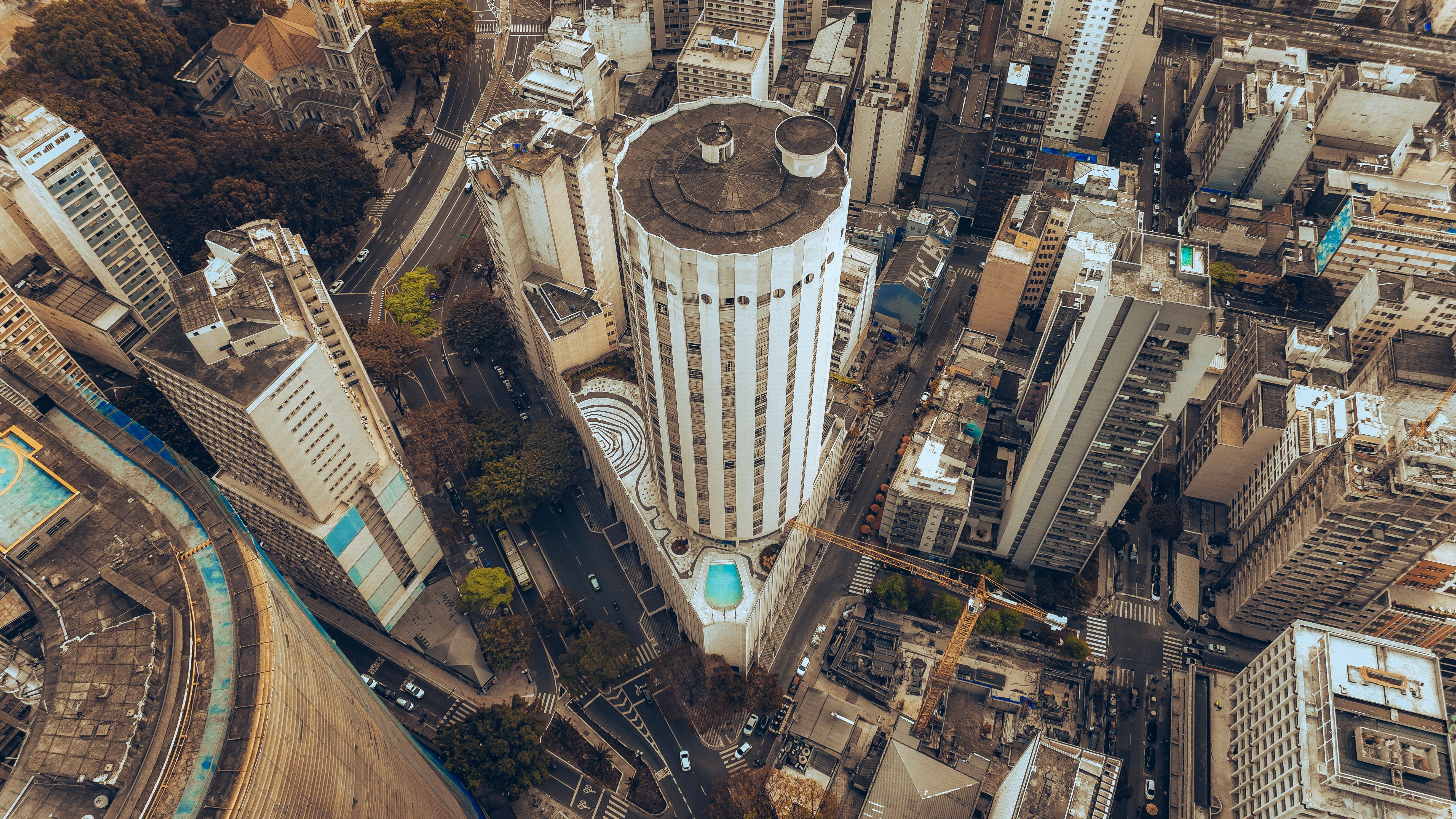 A high aerial view over dense central São Paulo, with a cylindrical tower among packed high-rise blocks.