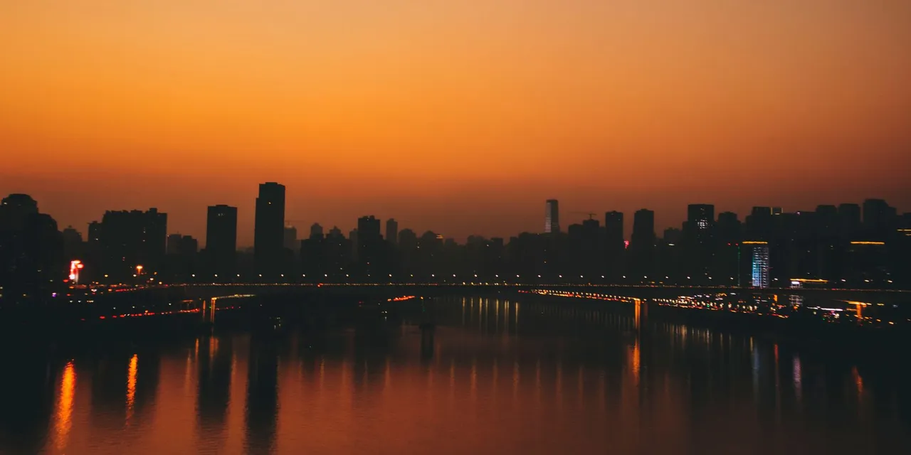 Stunning sunset over Chongqing skyline with river reflections creating a vibrant cityscape.