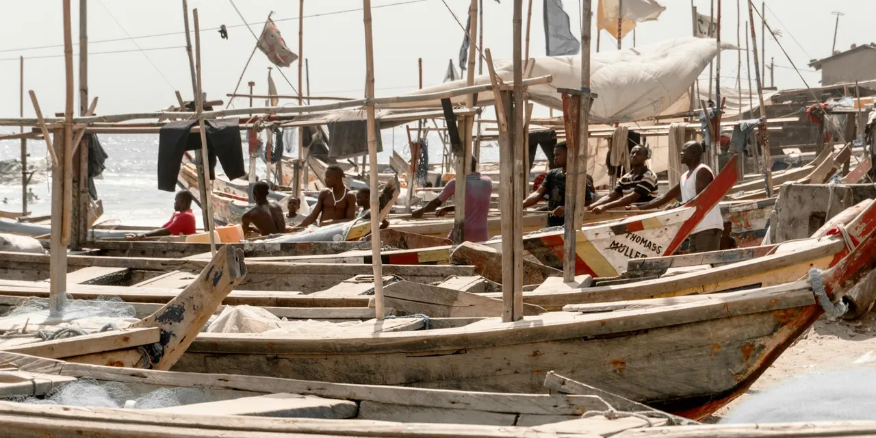 Traditional fishing boats lined up on Elmina beach in Ghana, showcasing local maritime culture.