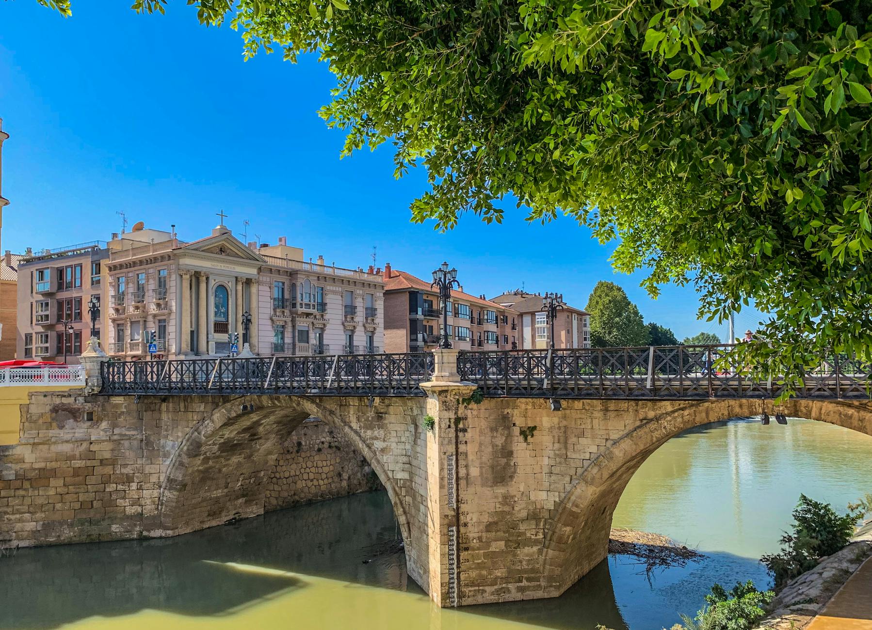 Scenic view of a historic Roman bridge in Murcia, Spain with clear blue sky.
