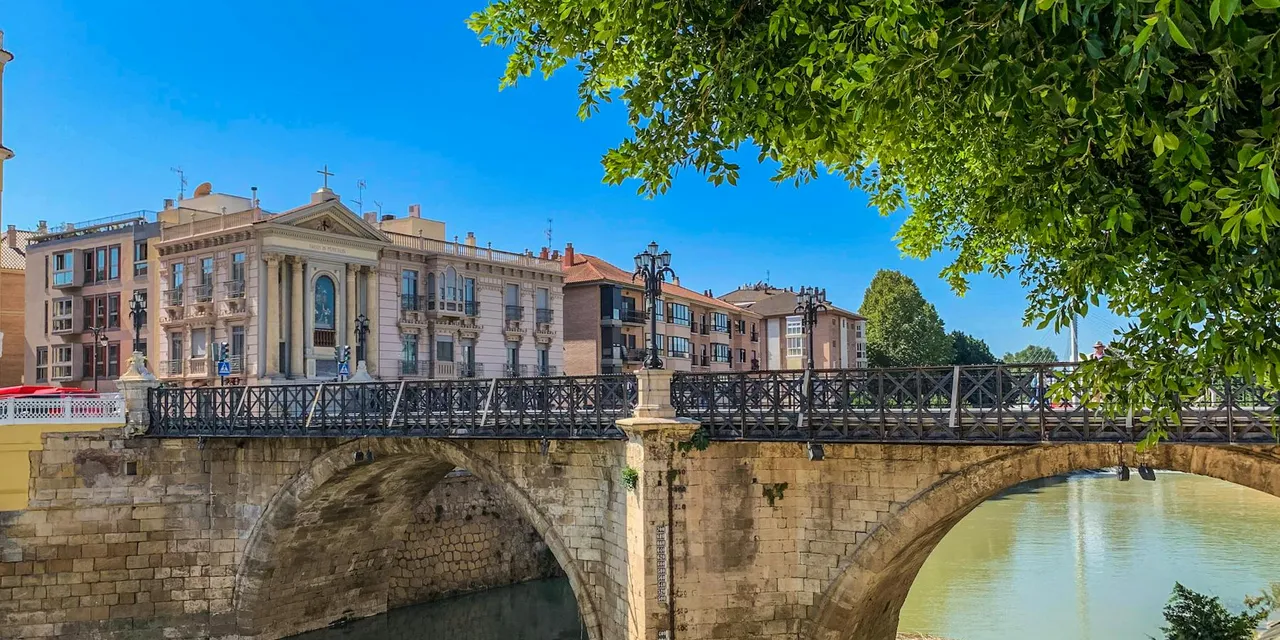 Scenic view of a historic Roman bridge in Murcia, Spain with clear blue sky.