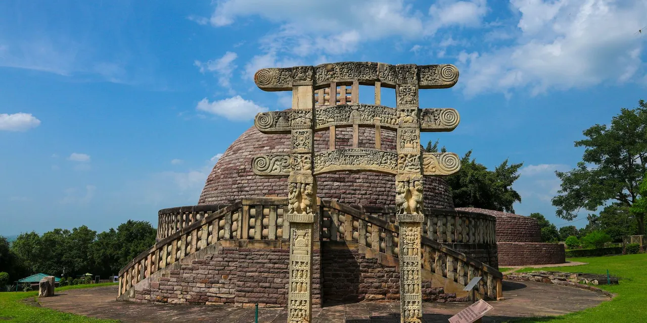 Ancient Sanchi Stupa with intricate carvings against a vibrant blue sky in Madhya Pradesh, India.