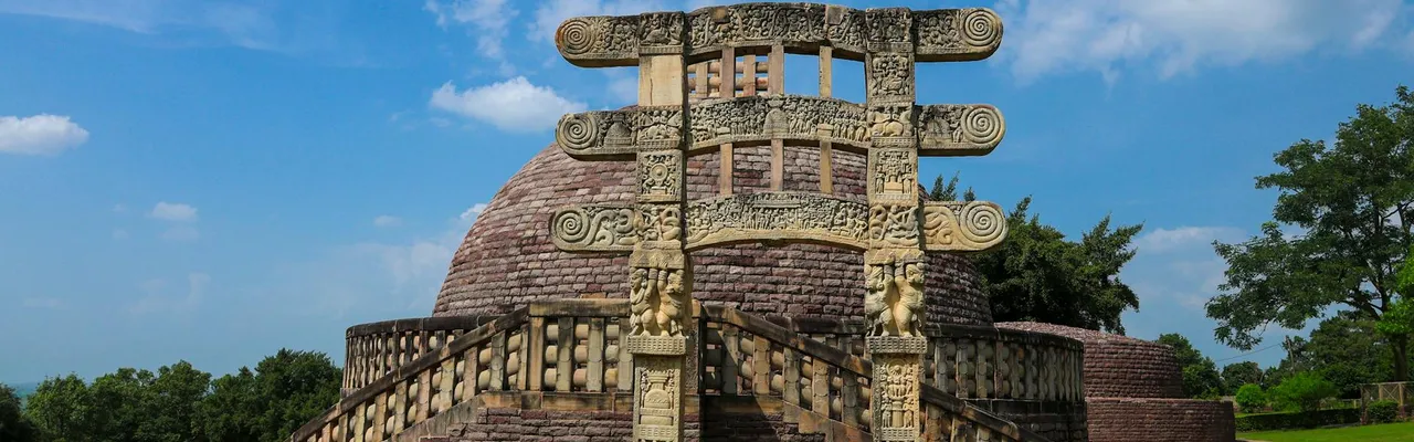 Ancient Sanchi Stupa with intricate carvings against a vibrant blue sky in Madhya Pradesh, India.
