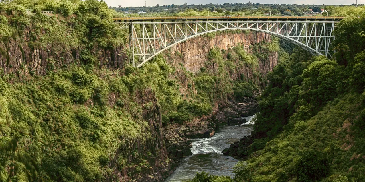 Victoria Falls Bridge gracefully arcs over the lush Batoka Gorge in Zimbabwe, showcasing stunning natural beauty.