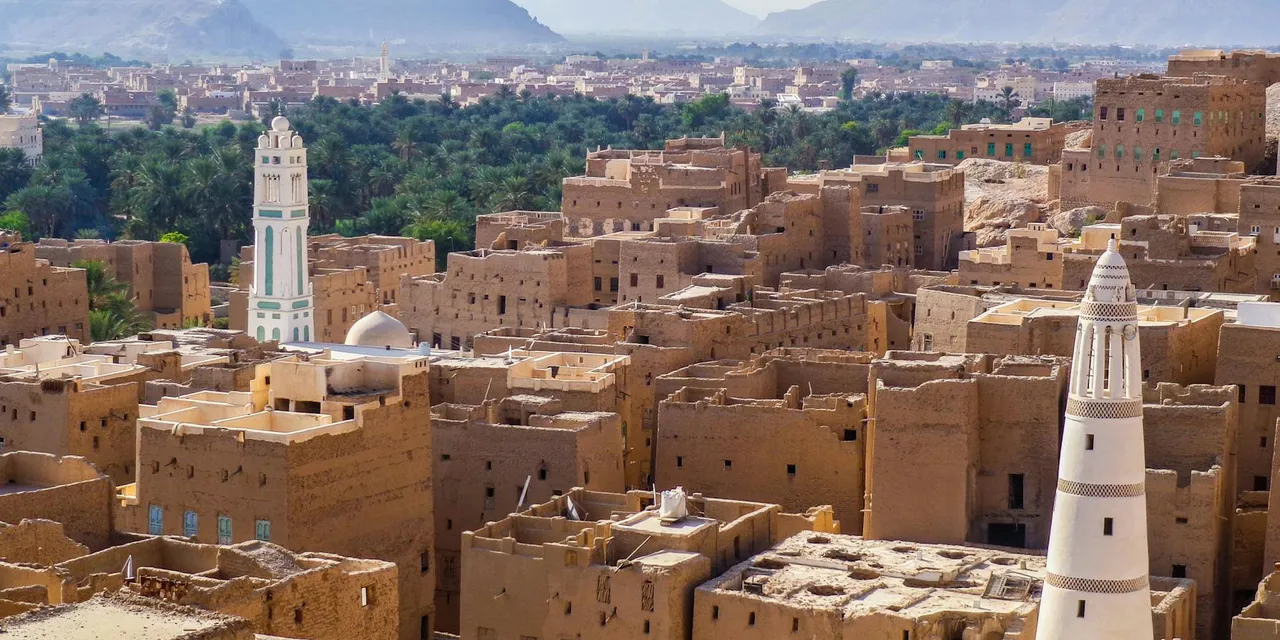 Aerial view showcasing the traditional architecture of a historic town in Yemen with iconic towers and desert landscape.