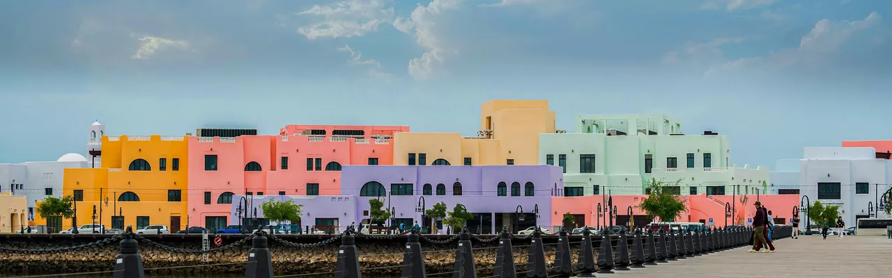 Pastel-coloured waterfront buildings along the Doha corniche promenade, Qatar