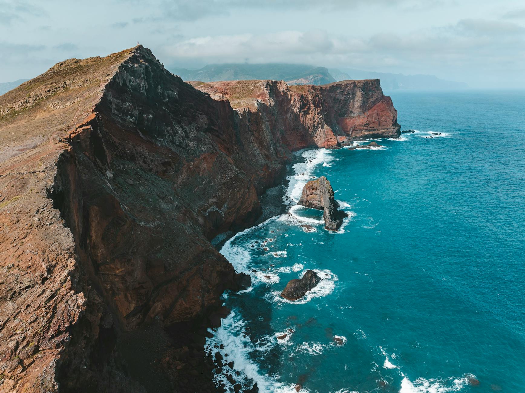 Stunning aerial drone view of Madeira’s cliffs and clear blue ocean, showcasing nature's beauty in Portugal.