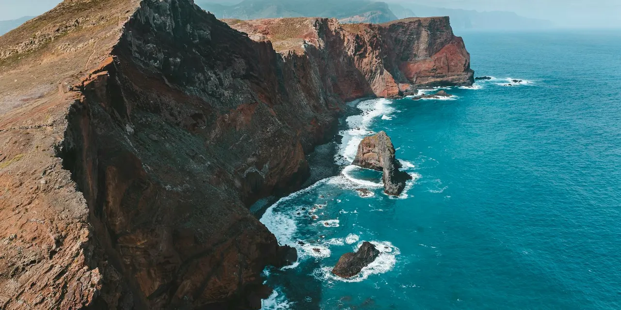 Stunning aerial drone view of Madeira’s cliffs and clear blue ocean, showcasing nature's beauty in Portugal.