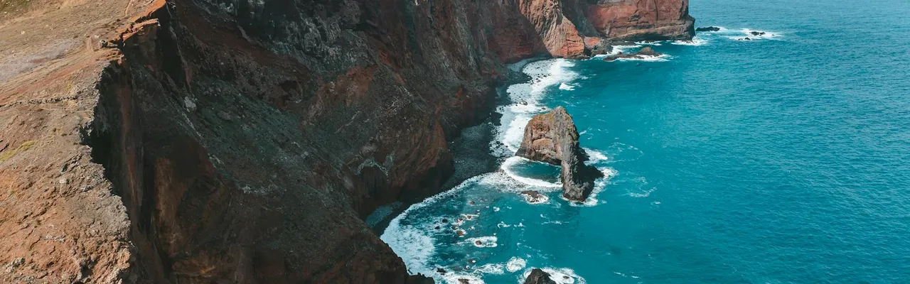 Stunning aerial drone view of Madeira’s cliffs and clear blue ocean, showcasing nature's beauty in Portugal.