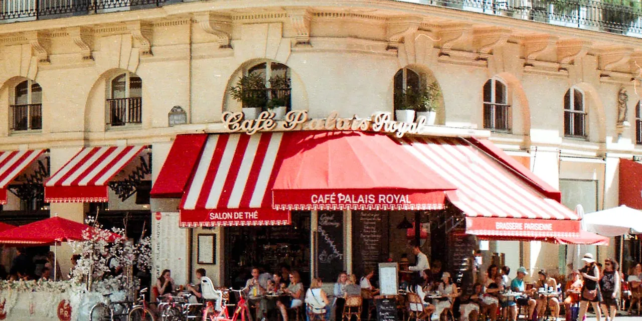 A bustling scene at Café Palais Royal in Paris with patrons enjoying a sunny day.