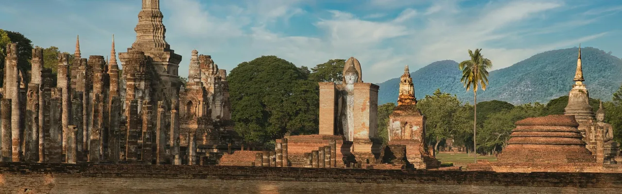 Ancient temple ruins of Sukhothai Historical Park with Buddha statues and stupas, Thailand