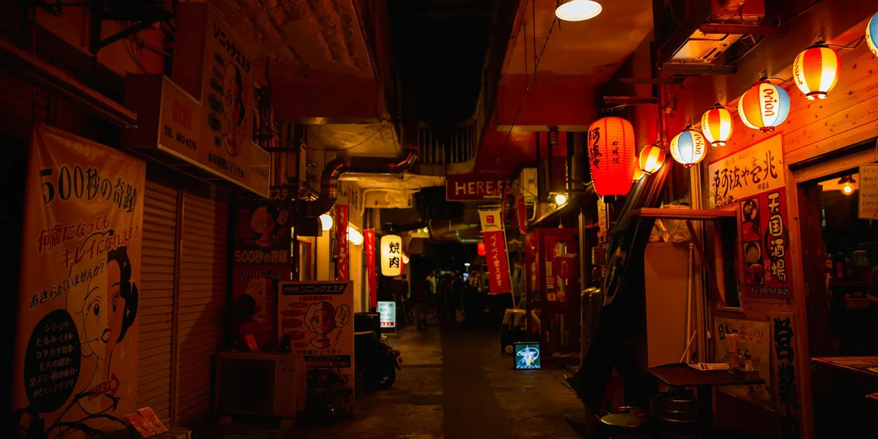 Narrow walkway between street shops with shiny lamps in Asian town at night