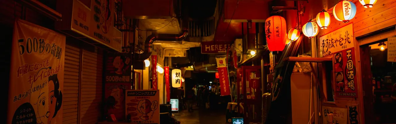 Narrow walkway between street shops with shiny lamps in Asian town at night