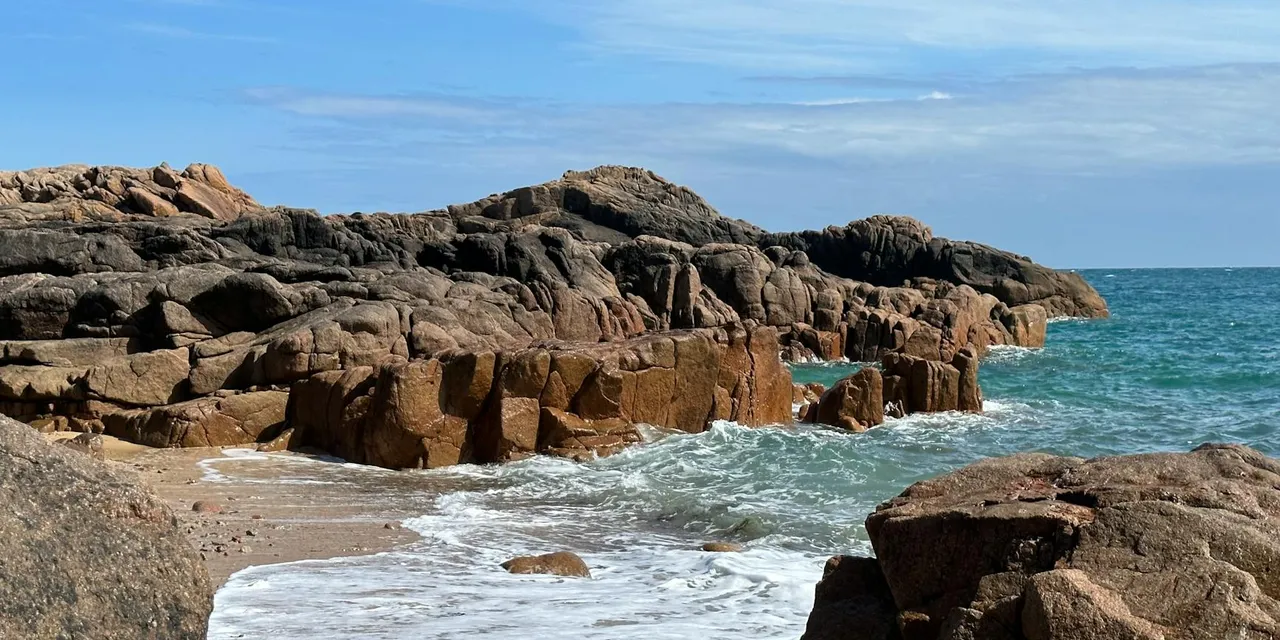 Scenic view of rocky coastline with waves crashing at Corbiere Point, Jersey. Perfect summer day for travel enthusiasts.