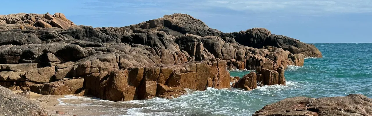 Scenic view of rocky coastline with waves crashing at Corbiere Point, Jersey. Perfect summer day for travel enthusiasts.