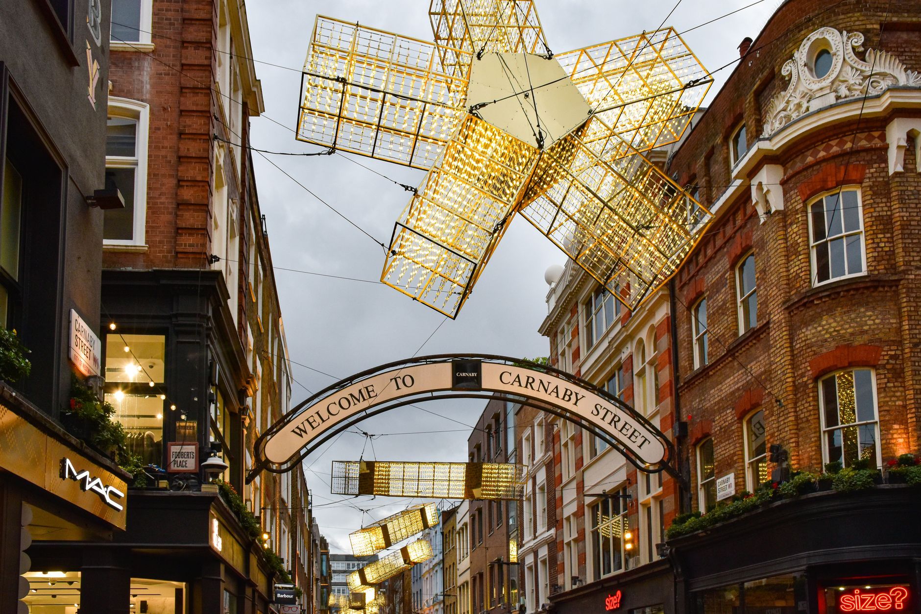 Bright festive lights on iconic Carnaby Street, London, showcasing vibrant city life.