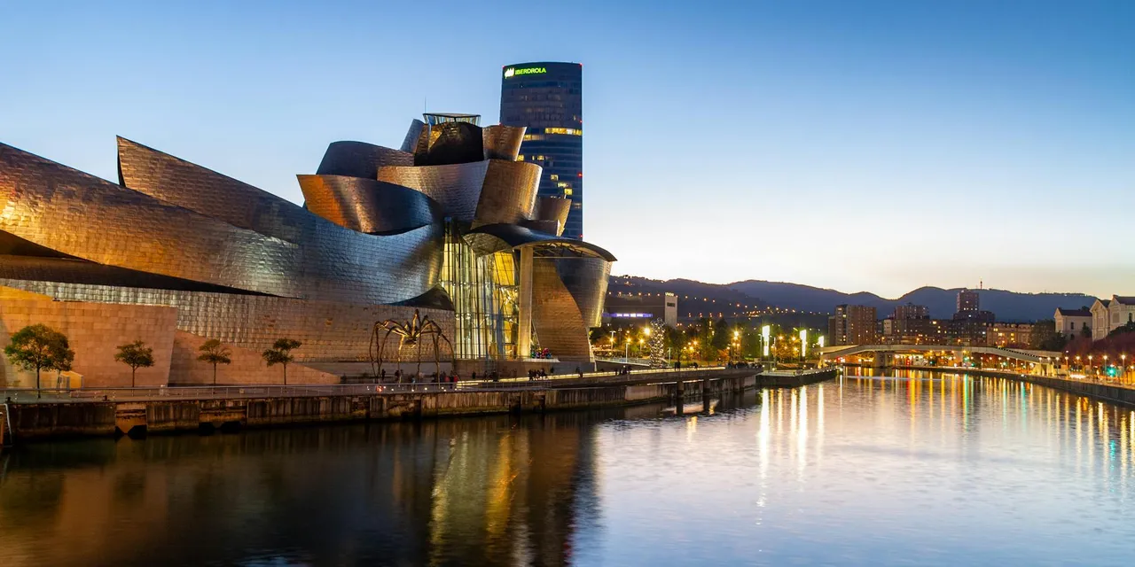 Stunning view of the Guggenheim Museum Bilbao reflecting in the Nervion River at dusk.