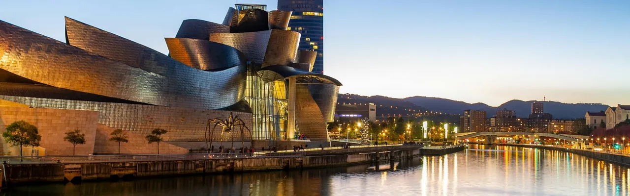 Stunning view of the Guggenheim Museum Bilbao reflecting in the Nervion River at dusk.
