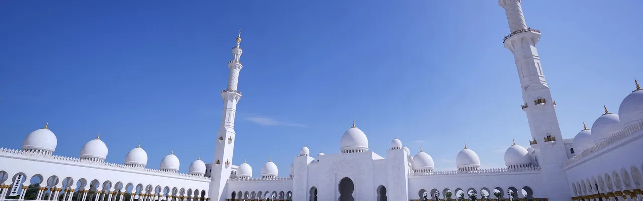 Sheikh Zayed Grand Mosque gleaming white courtyard under blue sky, Abu Dhabi, UAE