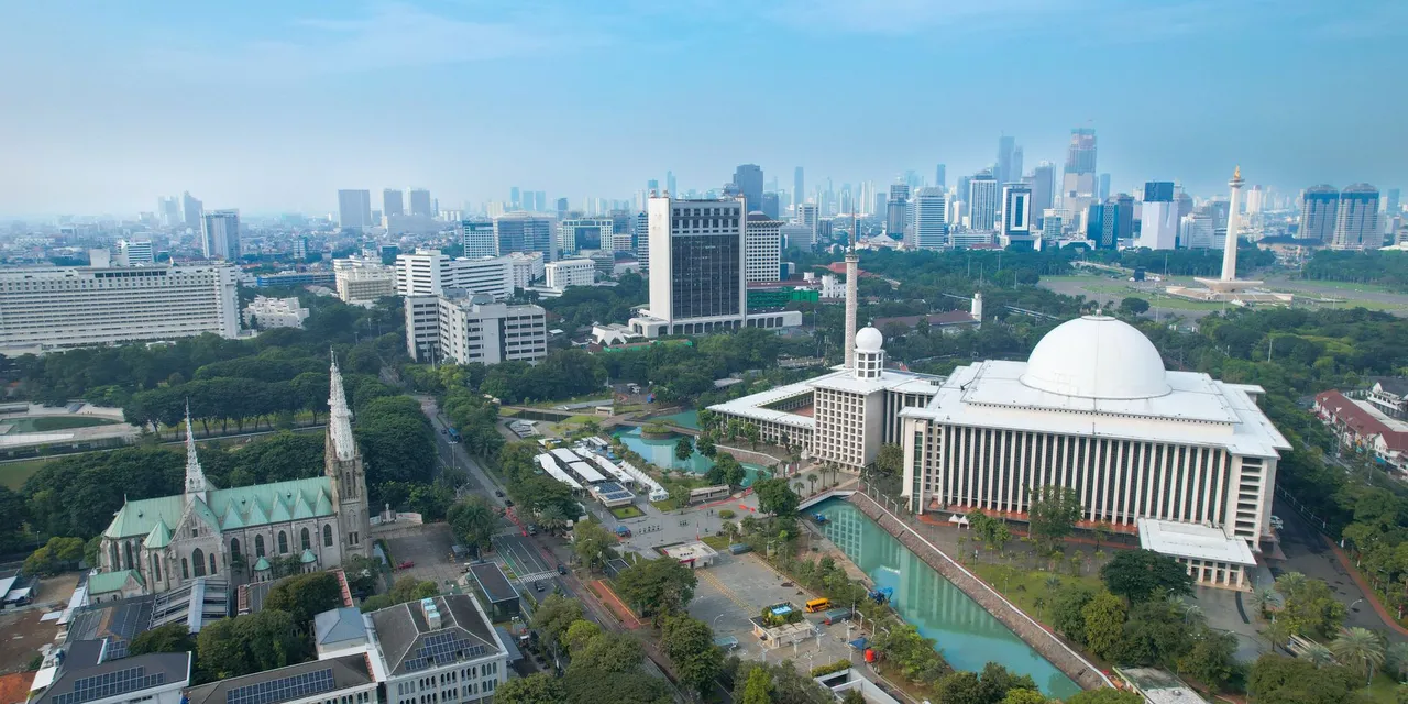 Stunning aerial shot of Istiqlal Mosque and Jakarta's modern skyline.