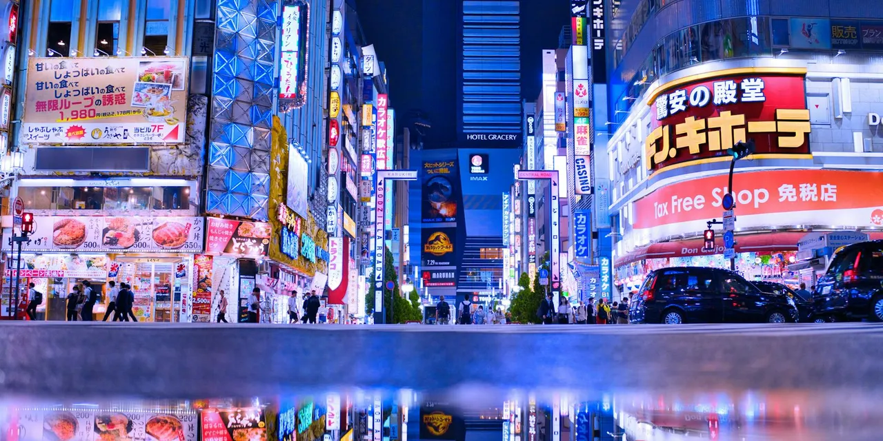 Bright neon lights and bustling activity in Shinjuku, Tokyo at night.