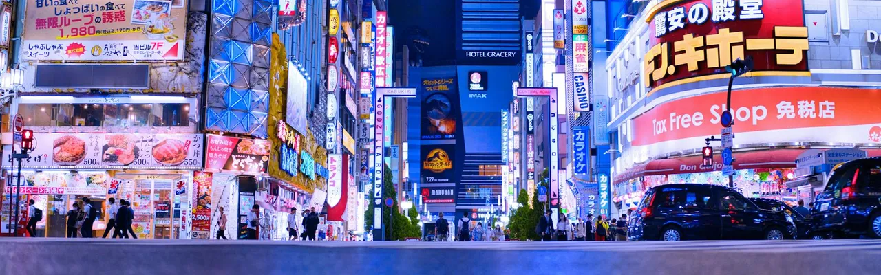 Bright neon lights and bustling activity in Shinjuku, Tokyo at night.