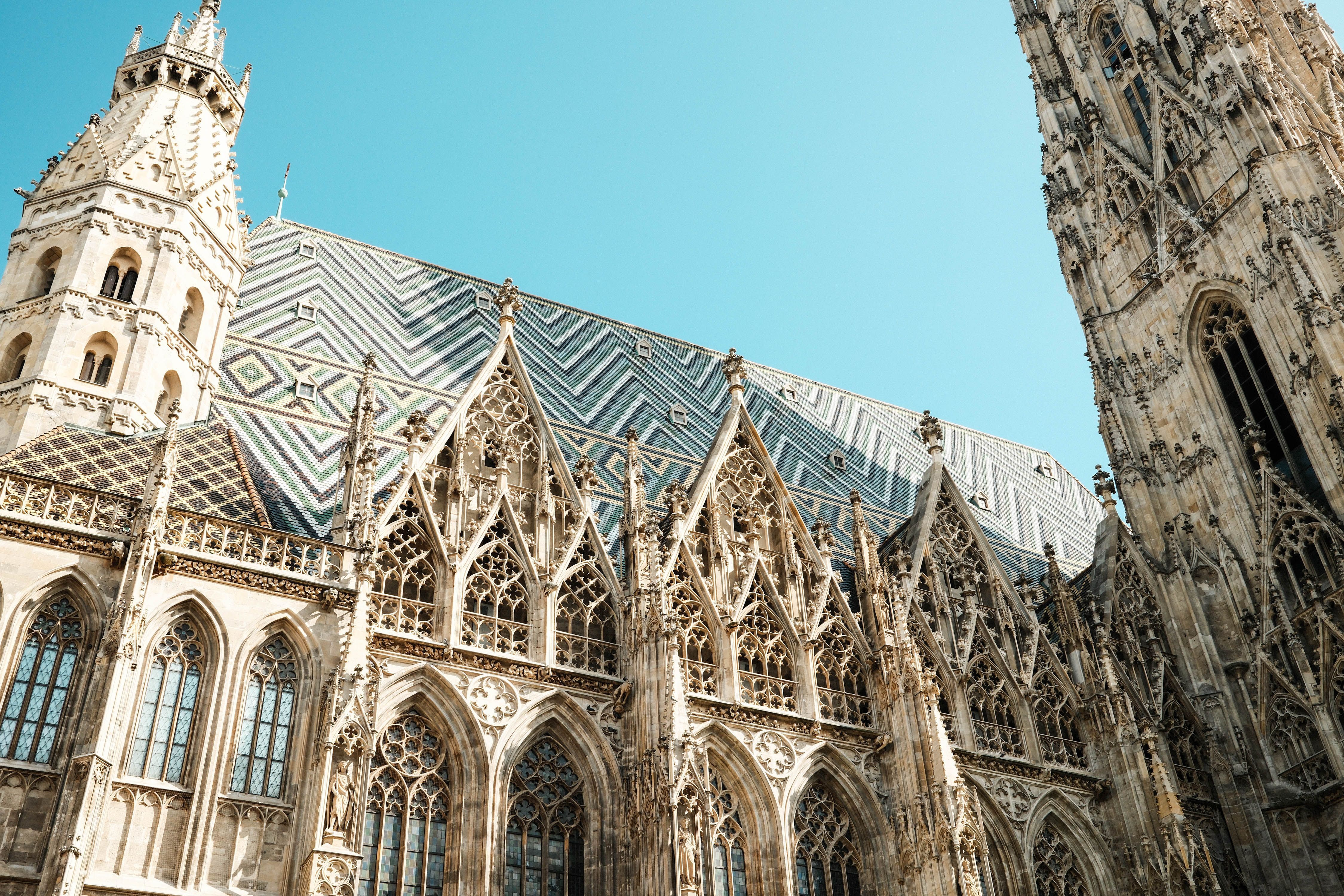 The patterned tiled roof and Gothic stonework of St Stephen's Cathedral in Vienna against a clear sky.