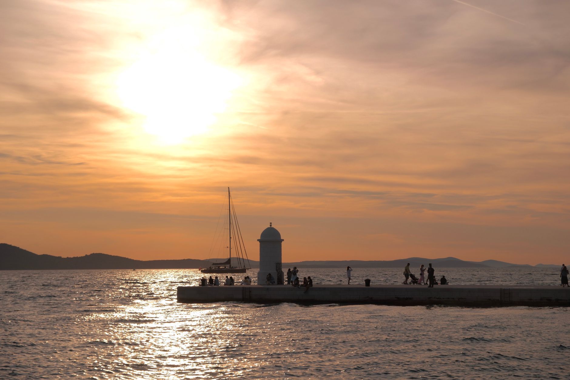 Beautiful sunset at Zadar promenade with people enjoying the view over the Adriatic Sea.