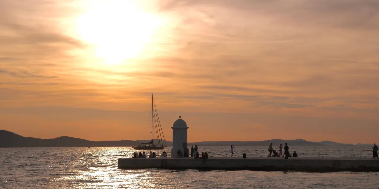 Beautiful sunset at Zadar promenade with people enjoying the view over the Adriatic Sea.