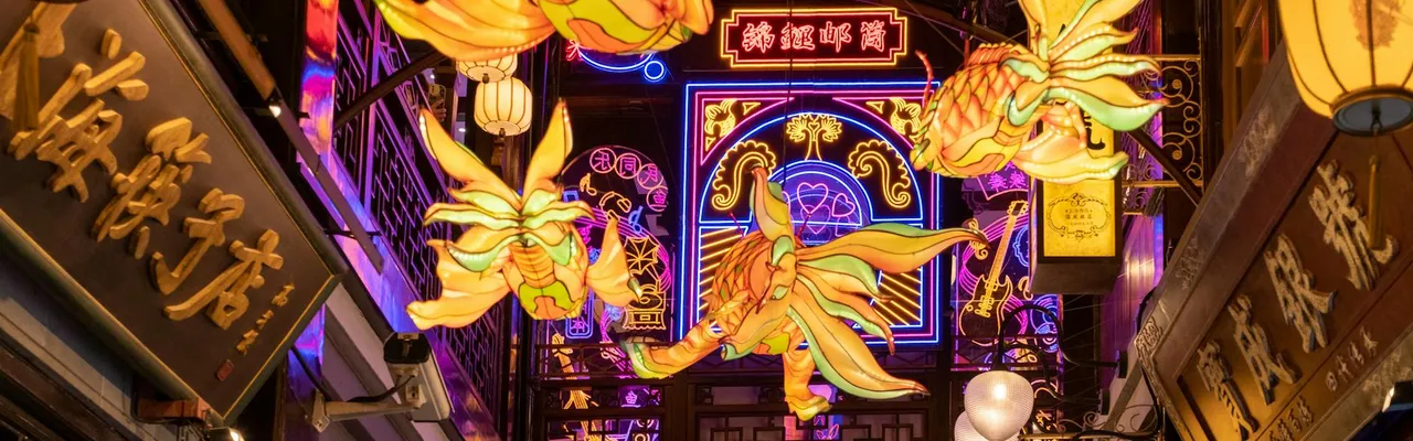Colorful lantern display illuminating a bustling urban alley at night.