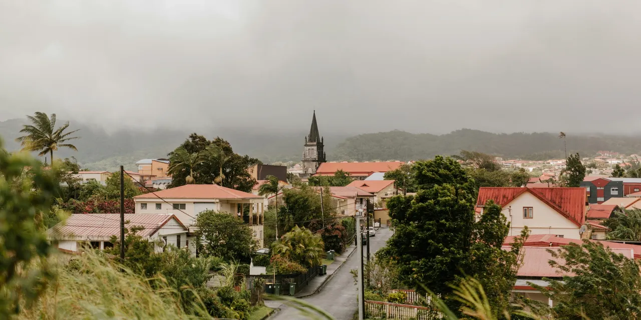 Hilltop view of a Martinique village with red-roofed houses and a church steeple amid tropical greenery