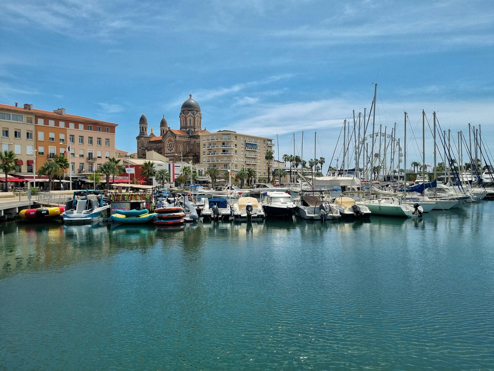 Scenic view of Saint-Tropez marina with boats and the iconic cathedral on a sunny day.