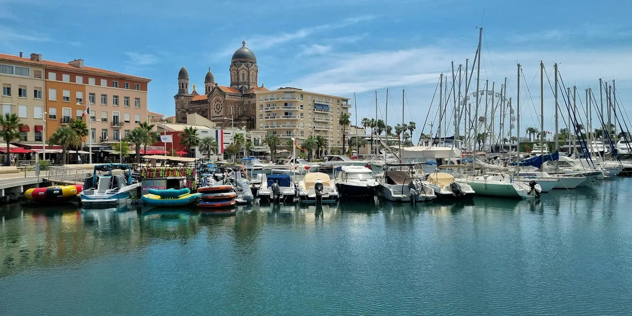 Scenic view of Saint-Tropez marina with boats and the iconic cathedral on a sunny day.