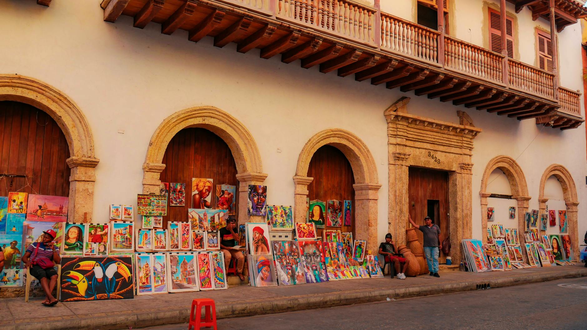 Colorful paintings on a charming Cartagena street attracting tourists with local culture.