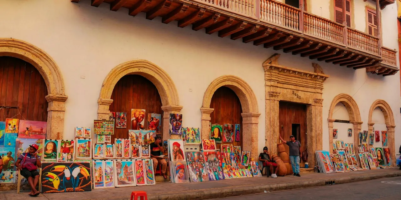 Colorful paintings on a charming Cartagena street attracting tourists with local culture.